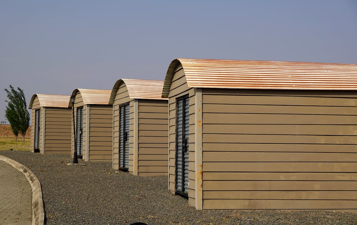 Modern modular storage units with slanted roofs and wood siding placed on gravel terrain.