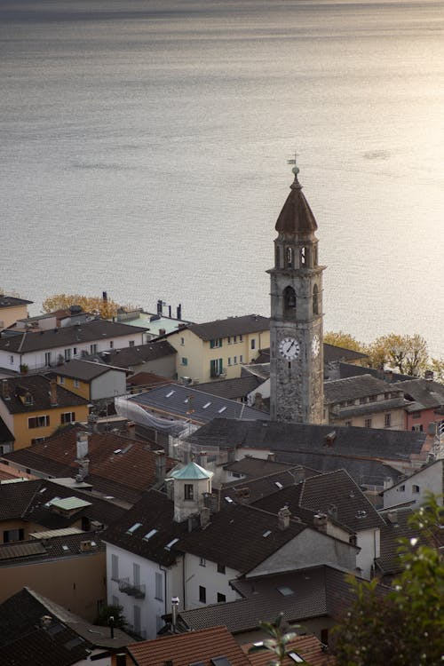 A small Swiss-style church sits beside a calm lake, surrounded by mountains.