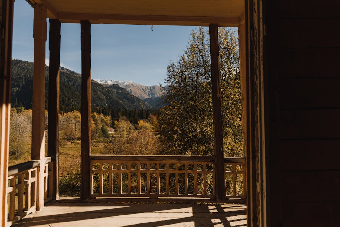 A scenic autumn view of a forested mountain range from a wooden deck terrace.