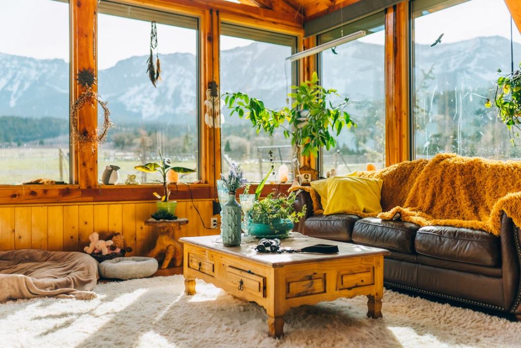 A cozy living room with a modern gray sofa, coffee table, and potted plant near a large window.