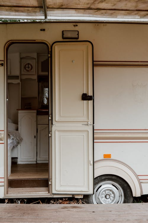 A white van with its side door open, parked outdoors near industrial buildings.