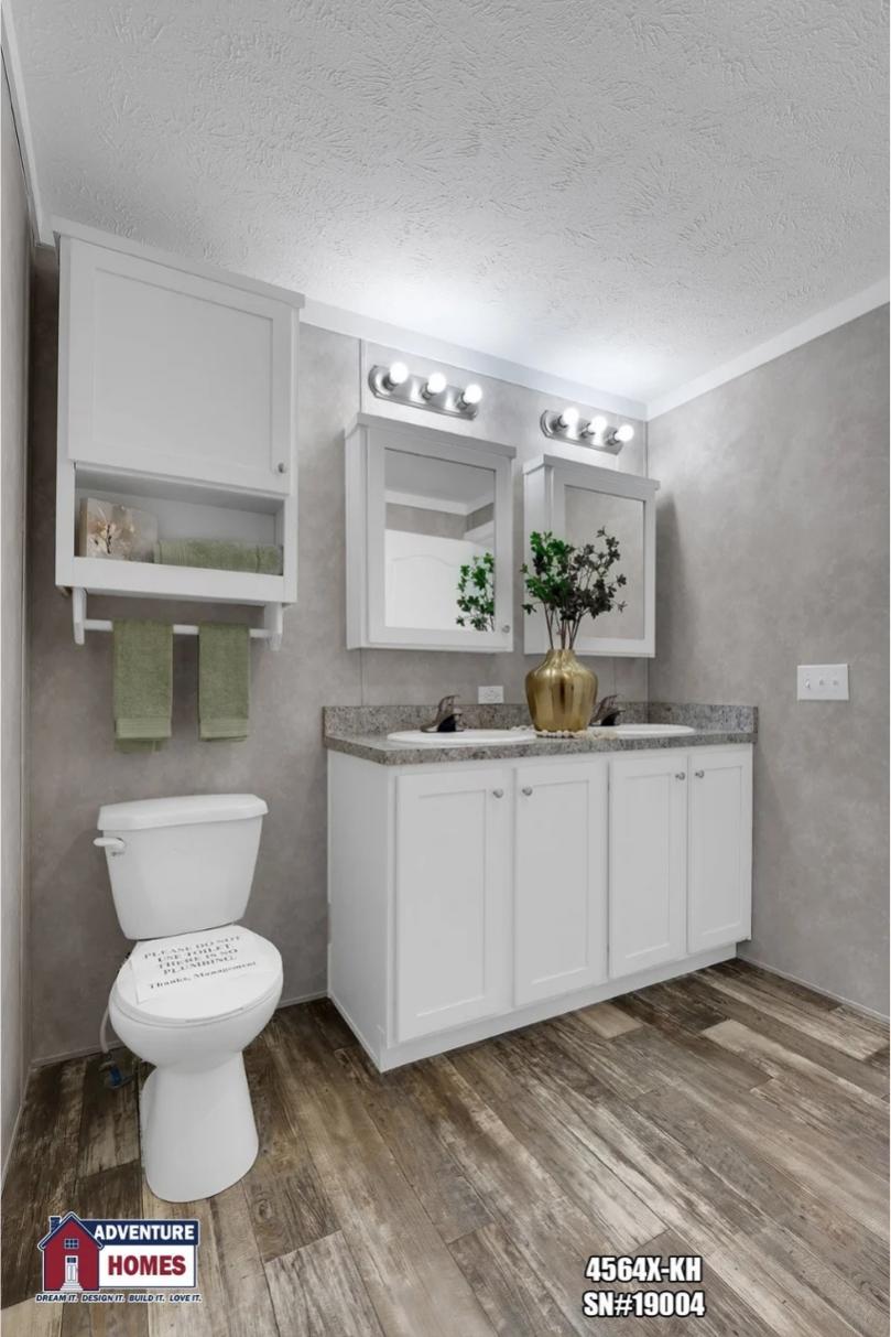 A master bathroom with white cabinetry, two mirrors, and vessel sinks against a wood-paneled wall
